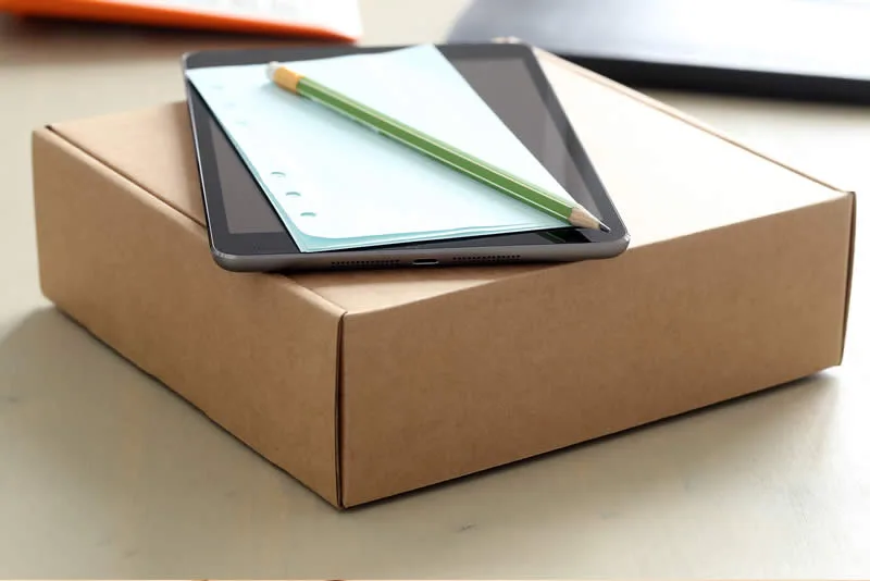 Verzenddoos met tablet en notitieblok op een bureau